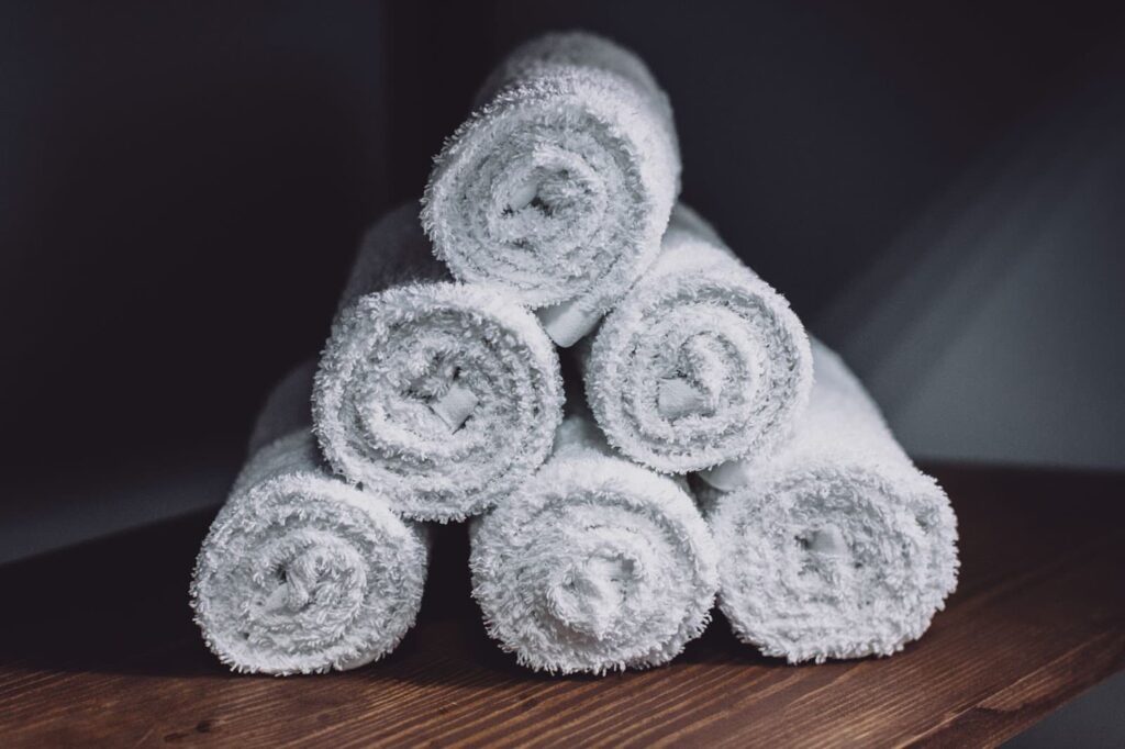 rolled and prepared white damp towels on a wooden table