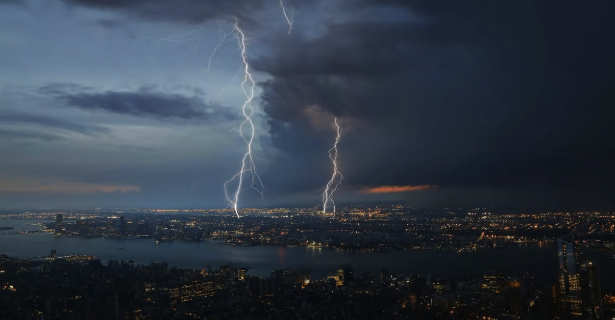 A panoramic view of the city at night with a dramatic lightning strike.