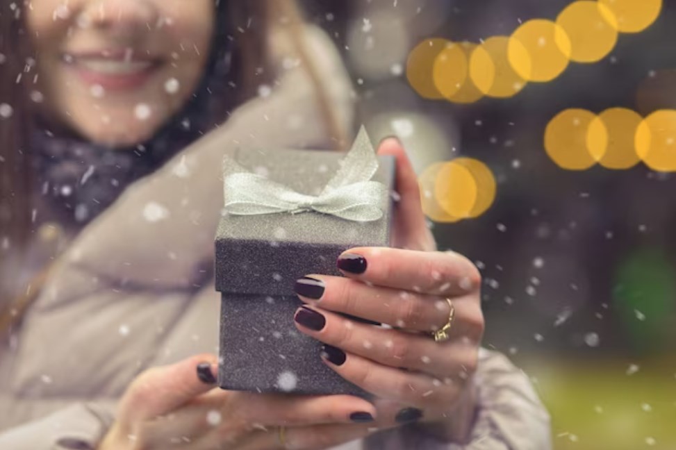 a woman opens a small gift box with a bow during the snowfall