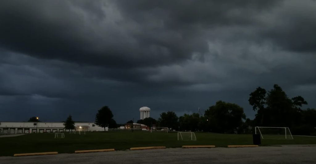 An open soccer field under dark clouds, foreshadowing an impending rainstorm.