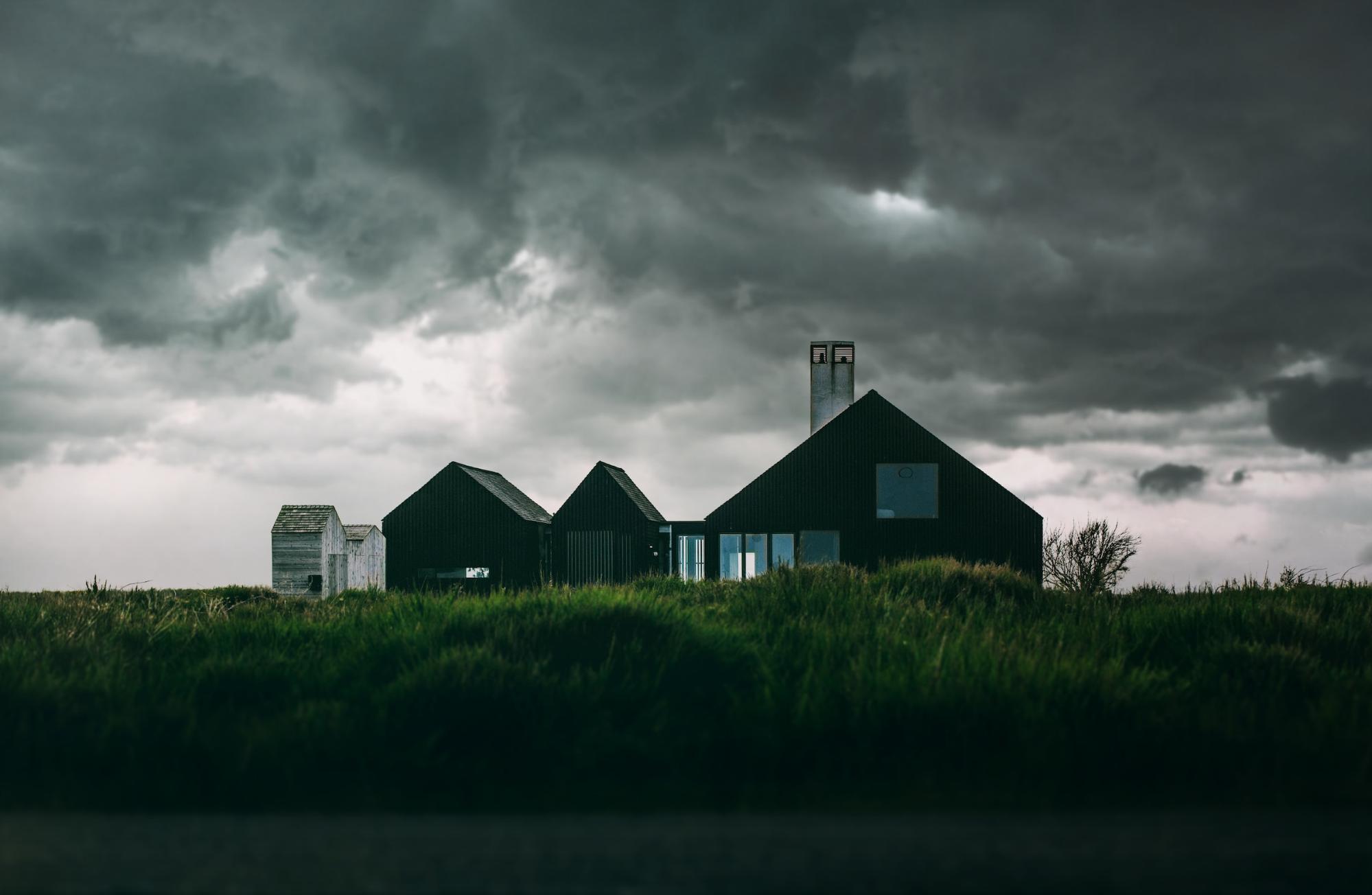 A house standing in green grass under dark clouds