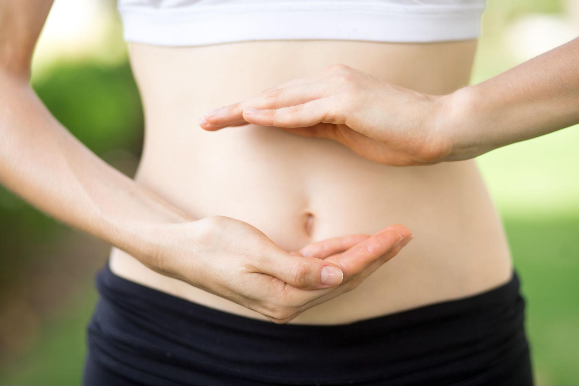 a close-up of a young woman's hands and slim belly